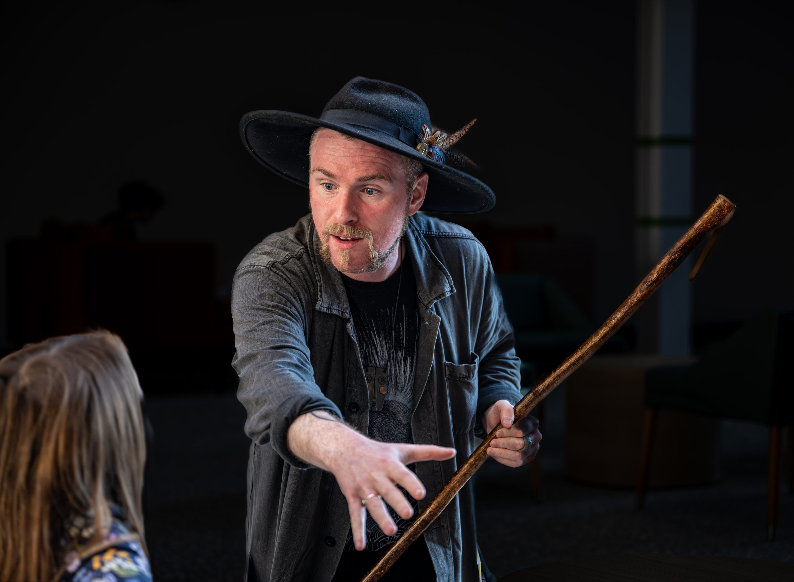 Ceri wearing his wide brimmed hat holding a staff telling a young listener a story